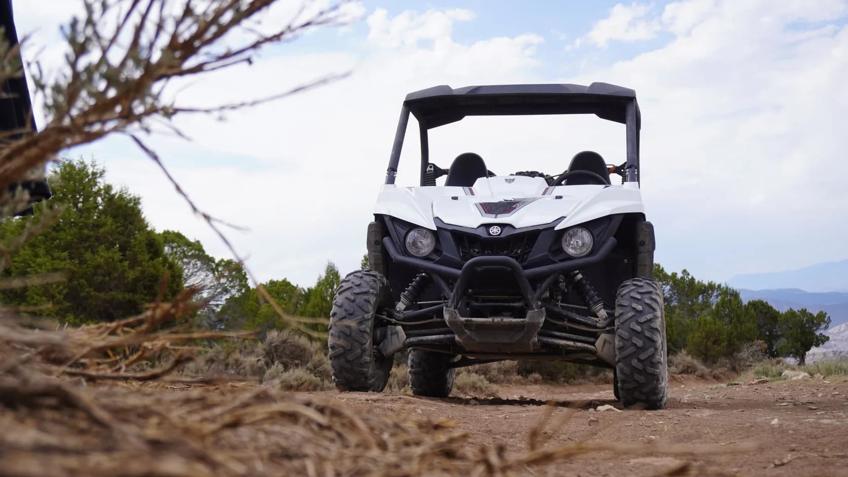 A side-by-side parked on a dirt trail with mountains behind
